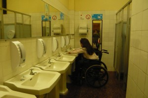 Fotografia del taller que muestra a persona usando una silla de ruedas en un baño lavándose las manos