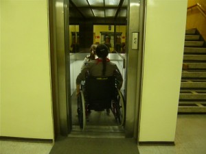 Fotografia del taller que muestra a persona usando una silla de ruedas para entrar a un ascensor